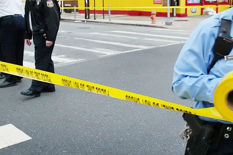 Philadelphia police run crime scene tape.