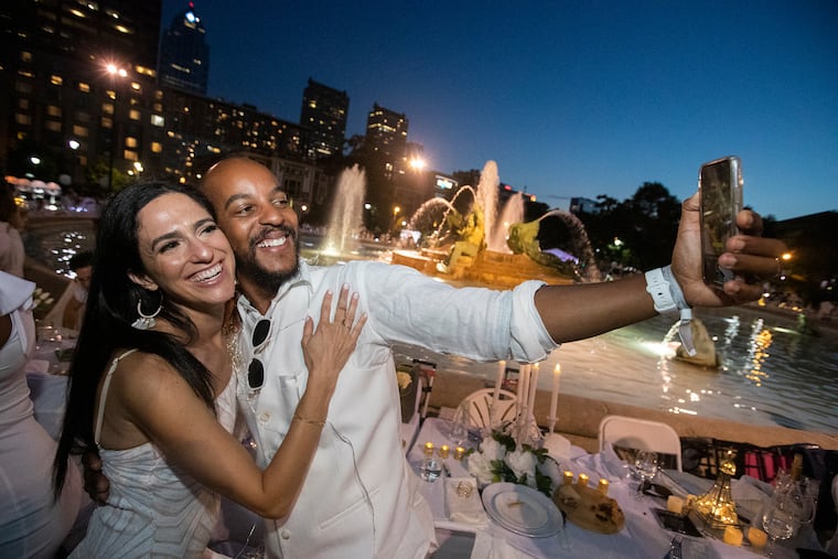 Lauren and Stephon Proctor take a photo of themselves in front of the fountain at Logan Circle during the 10th annual Diner en Blanc.
