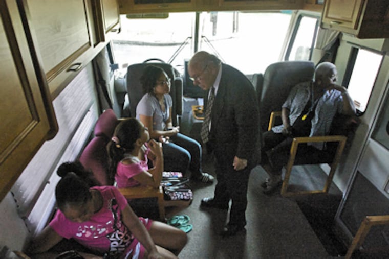 Lawrence Ragone chats with patients inside the mobile eye clinic. In 1961, he founded the Camden Eye Center. Now 81, he has been out with the mobile clinic six times this month alone. (John Costello / Staff Photographer)