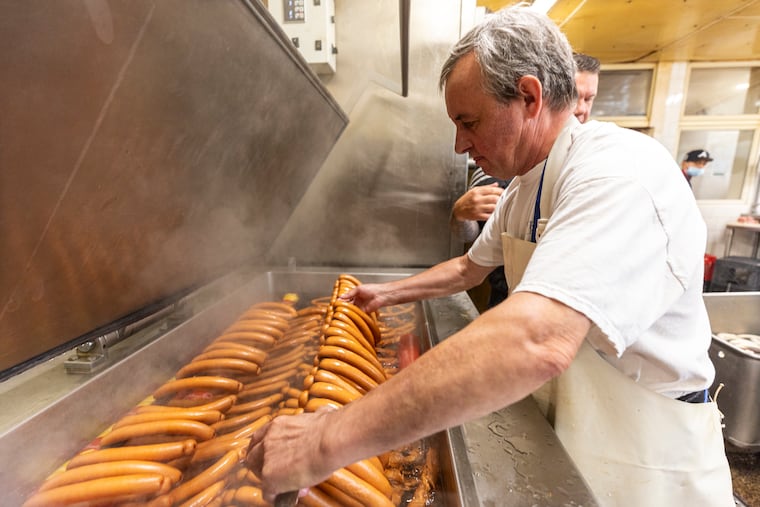 Alex Naumenko, 64, of Northeast Philadelphia, Pa., Sausage Maker, pulls wieners from a water bath after cooking at Rieker’s Meats in Philadelphia, Pa., on Tuesday, July 16, 2024.