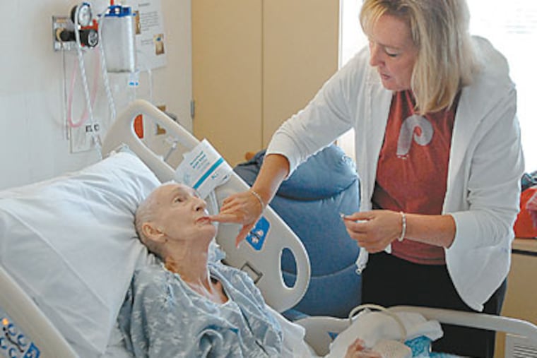 Beth Anne Tole moistens the lips of her mother, Mary, at Abington Memorial Hospital. After Mary fell seriously ill at 74, a palliative care team helped the family confront difficult medical decisions. (TOM GRALISH / Staff Photographer)