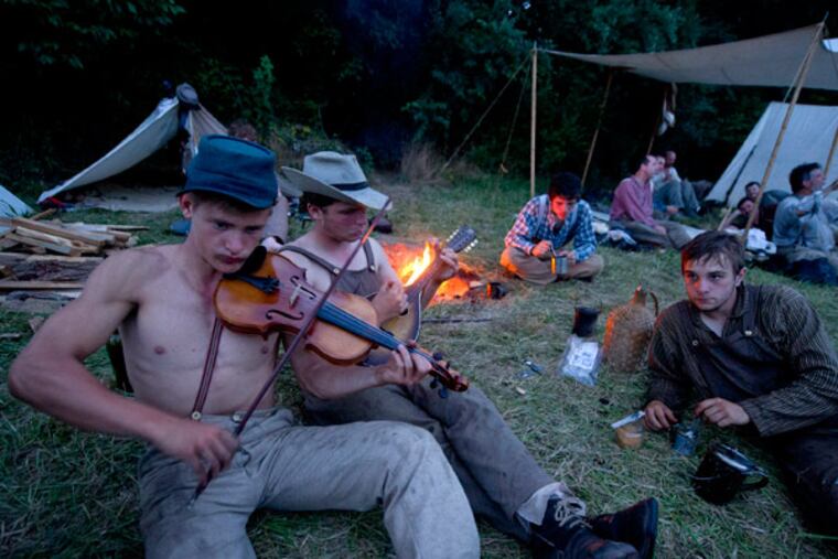 Confederate Civil War reenactors Will Gondy (foreground), 17, and Sam Leamer, 16, both of Elverson, PA, provide music to their fellow soldiers in camp on the night July 5, 2013 after participating in two battles on a farm outside Gettysburg as part of the 150th anniversary of the decisive Civil War battle. ( CLEM MURRAY / Staff Photographer )