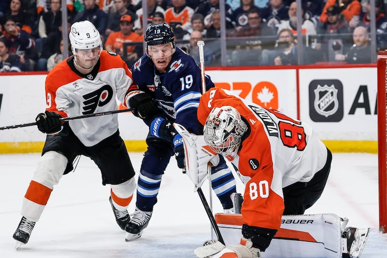 The Jets' Jonathan Toews digs for the rebound as Flyers goaltender Dan Vladar makes a save Saturday with Jamie Drysdale (left) moving in.