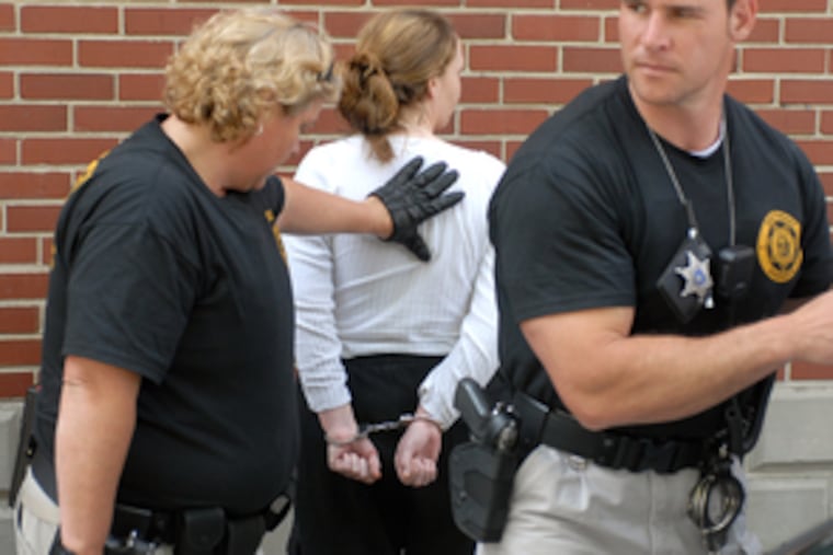 Deputies Joanne Plasterer and Greg Appleton of the Montgomery County Sheriff's Department handcuff Demeire Profeto outside her Valley Township home.