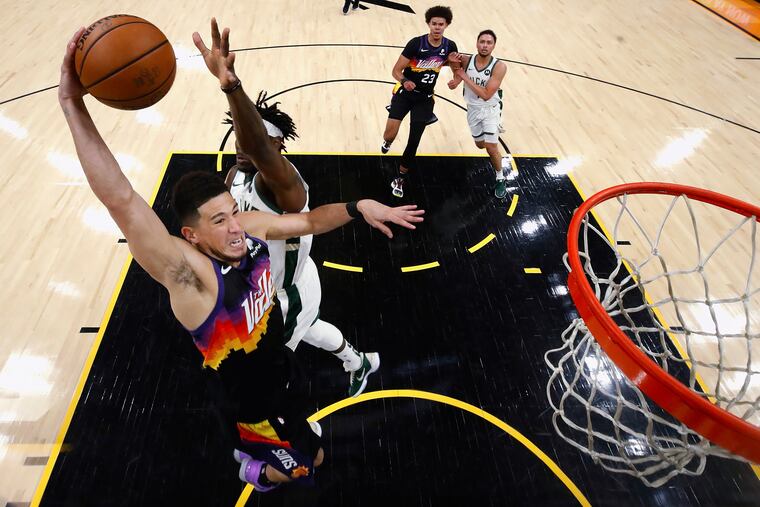 The Suns' Devin Booker goes up for a dunk over the Bucks' Jrue Holiday during the first half of Game 2.