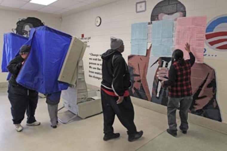 A poll worker, right, goes over a sample ballot with a voter, that is plastered over a mural of President Barack Obama in the voting area of polling place # 3518 at Benjamin Franklin Elementary School. A mural of President Barack Obama had to be covered in the school cafeteria after Republicans got a judge to issue an order that it must be covered so voters could not see the President's image as they waited to vote. (Michael Bryant/Staff)
