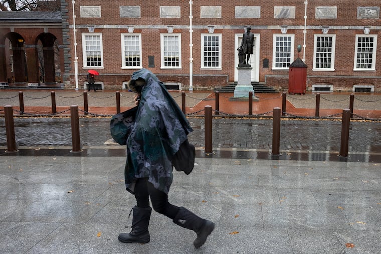 A man in poncho protects himself from the rain as he walks east on Chestnut Street in front of Independence Hall on a rainy day in Old City section of Philadelphia on Thursday, December 22, 2022.