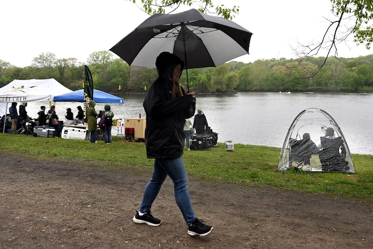 Parent spectators Julie and Dave Sun (right) of McLean, Virginia have their own personal shelter from the rain, among the school tents along the bank of the Schuylkill Sunday, April 19, 2026, during the 5th of the spring series Manny Flick / Horvat regattas.