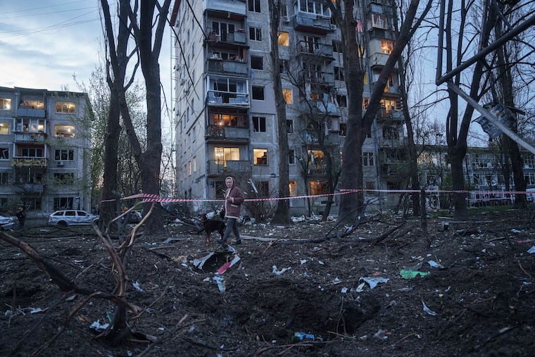 A woman with a dog walks among the rubble of a house damaged after a Russian strike Thursday on a residential area in Kyiv, Ukraine.