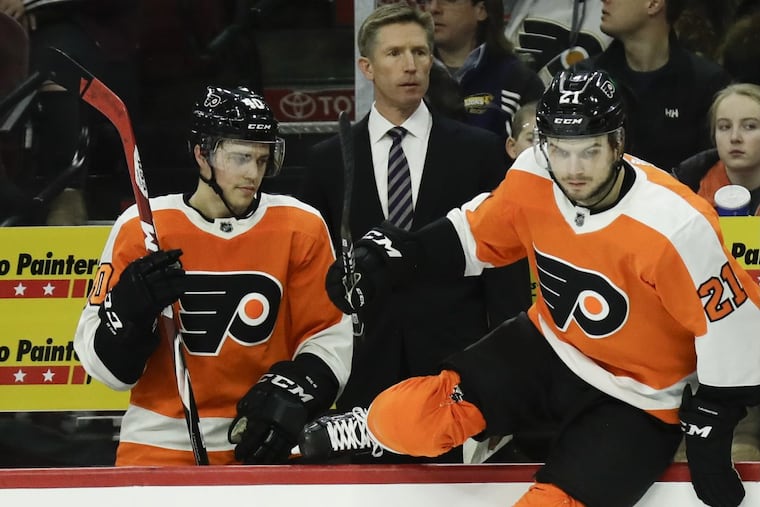 Flyers Head Coach Dave Hakstol watches his team next to center Travis Konecny and center Scott Laughton leaping on the ice against the St. Louis Blues on Saturday, January 6, 2018 in Philadelphia.