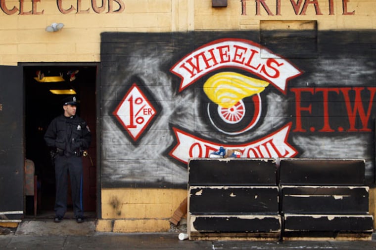 A police officer stands guard in front of the Wheels of Soul clubhouse in West Philadelphia. (David Maialetti / Staff Photographer)