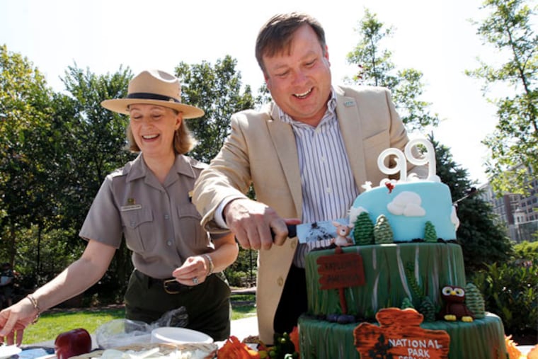 Sam Lemheney cuts the cake, with Cynthia MacLeod readying plates. (MICHAEL BRYANT/Staff Photographer)