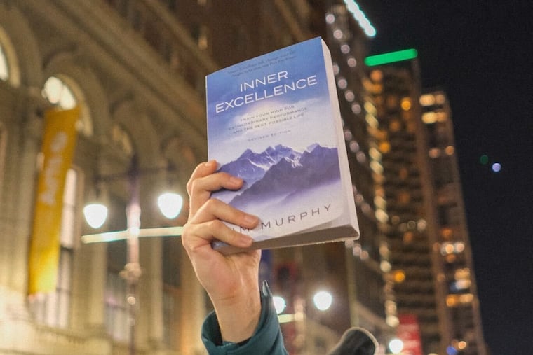 A reveler holds up a copy of 'Inner Excellence' by Jim Murphy, which Eagles wide receiver was seen reading on the sidelines of the divisional championship. The Eagles won the NFC championship, beating the Washington Commanders, on January 26, 2025.