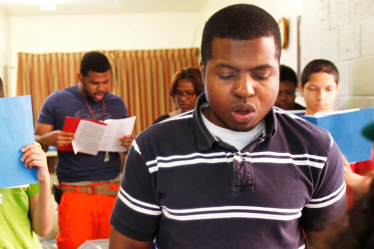 Pastor Jomo Johnson, right, sings with members of his church, Philly Open Air Church on 5th Street in North Philadelphia, during Sunday mass on May 12, 2013. ( DAVID MAIALETTI / Staff Photographer )