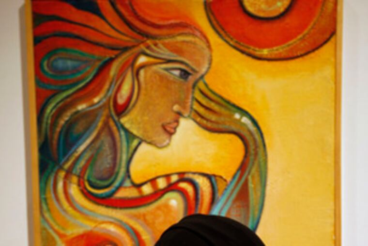 A woman regards an abstract portrait at the French Embassy in Riyadh, Saudi Arabia.