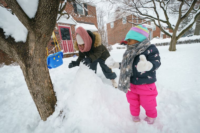 Latinya Jones and her daughter Lailah build a snowman in Norristown on Tuesday.