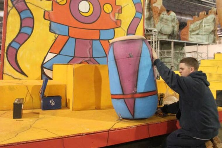 Saturnalians Fancy Brigade has a Mayan theme. Seamus Rudolph mounts a drum on a set at the Convention Center. (CHARLES FOX / Staff Photographer)