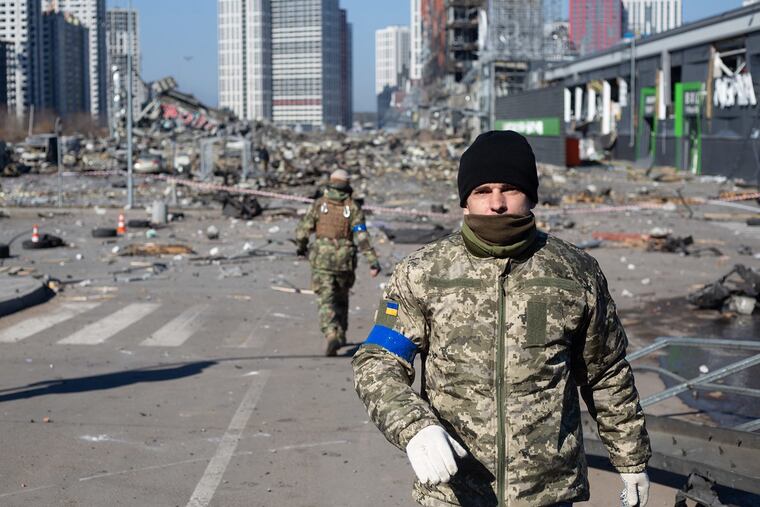 Ukrainian servicemen are seen at the explosion site after a rocket strike into a shopping mall on March 21 in Kyiv, Ukraine.
