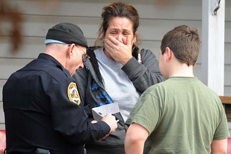 An officer talks with a neighbor of those living in a Souderton home where three victims were found, joined by her son.