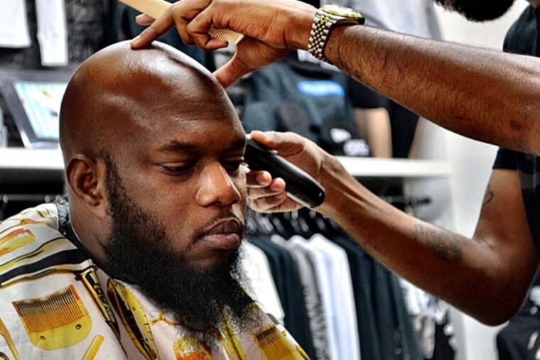 Barber Andre Scott, trimming up Freeway's fringe, says he has been using the product for several months. (Kaseem Green)