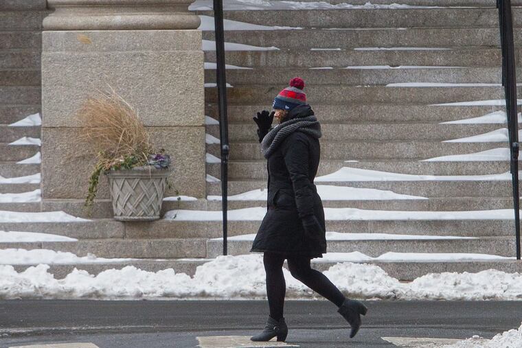 A pedestrian shields her face from the cold wind while walking in the Rittenhouse Square neighborhood in Philadelphia on Monday.