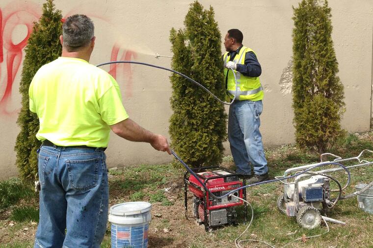 SEPTA workers Ricky DeLarso and Charles Randolph paint over graffiti.