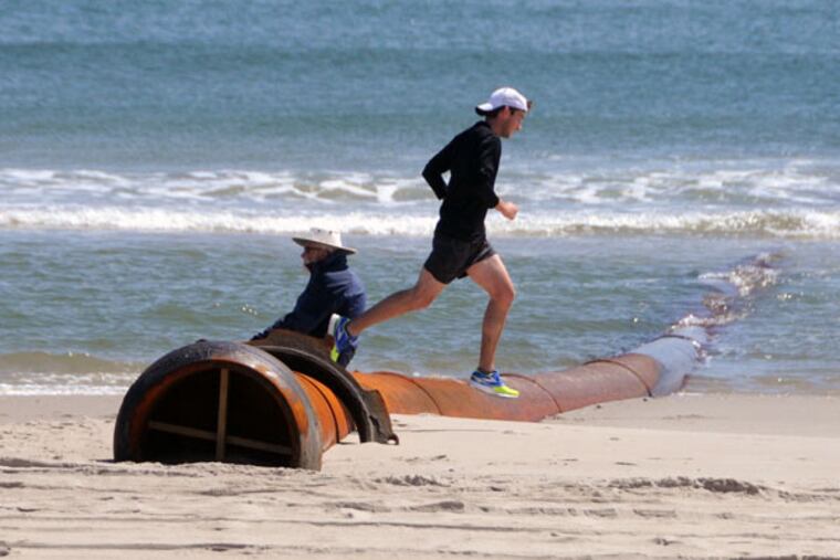 No obstacle: A runner on the beach at Ocean City hops over a dredge pipe that has been put in place on the beach at 43d Street. (CURT HUDSON)