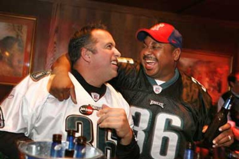 Paul Strickland (left) and Peter Graham are happy about an Eagles' score as they watch the Eagles-Vikings playoff game at the Fox and Hound in Center City. (Eric Mencher/Staff Photographer)