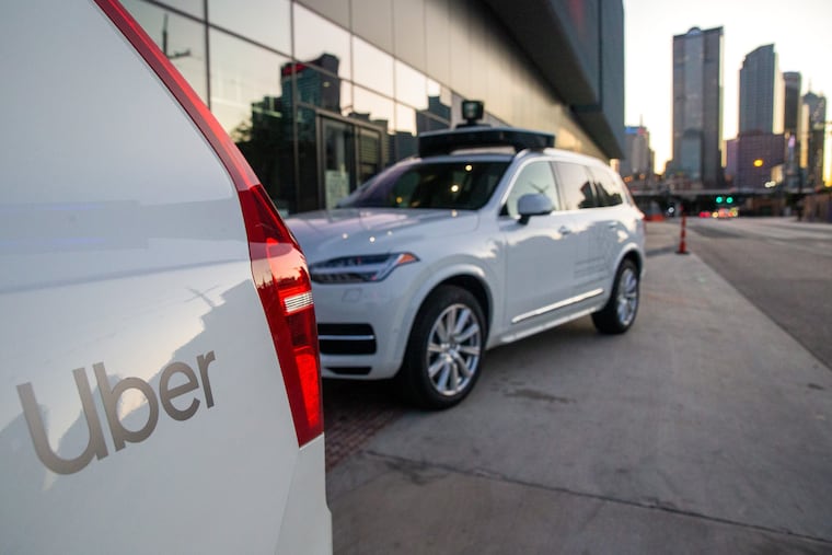 Self-driving Uber vehicles are parked in front of the Uber office in Dallas.
