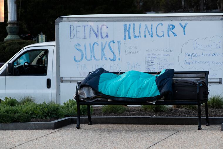 A man sleeps on a park bench in front of Tom Frey’s truck.