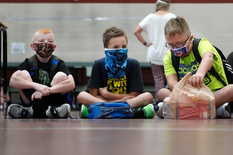 In this Aug. 5, 2020, file photo, wearing masks to prevent the spread of COVID19, elementary school students wait for classes to begin in Godley, Texas. As schools reopen around the country, their ability to quickly identify and contain coronavirus outbreaks before they get out of hand is about to be put to the test. (AP Photo/LM Otero, File)