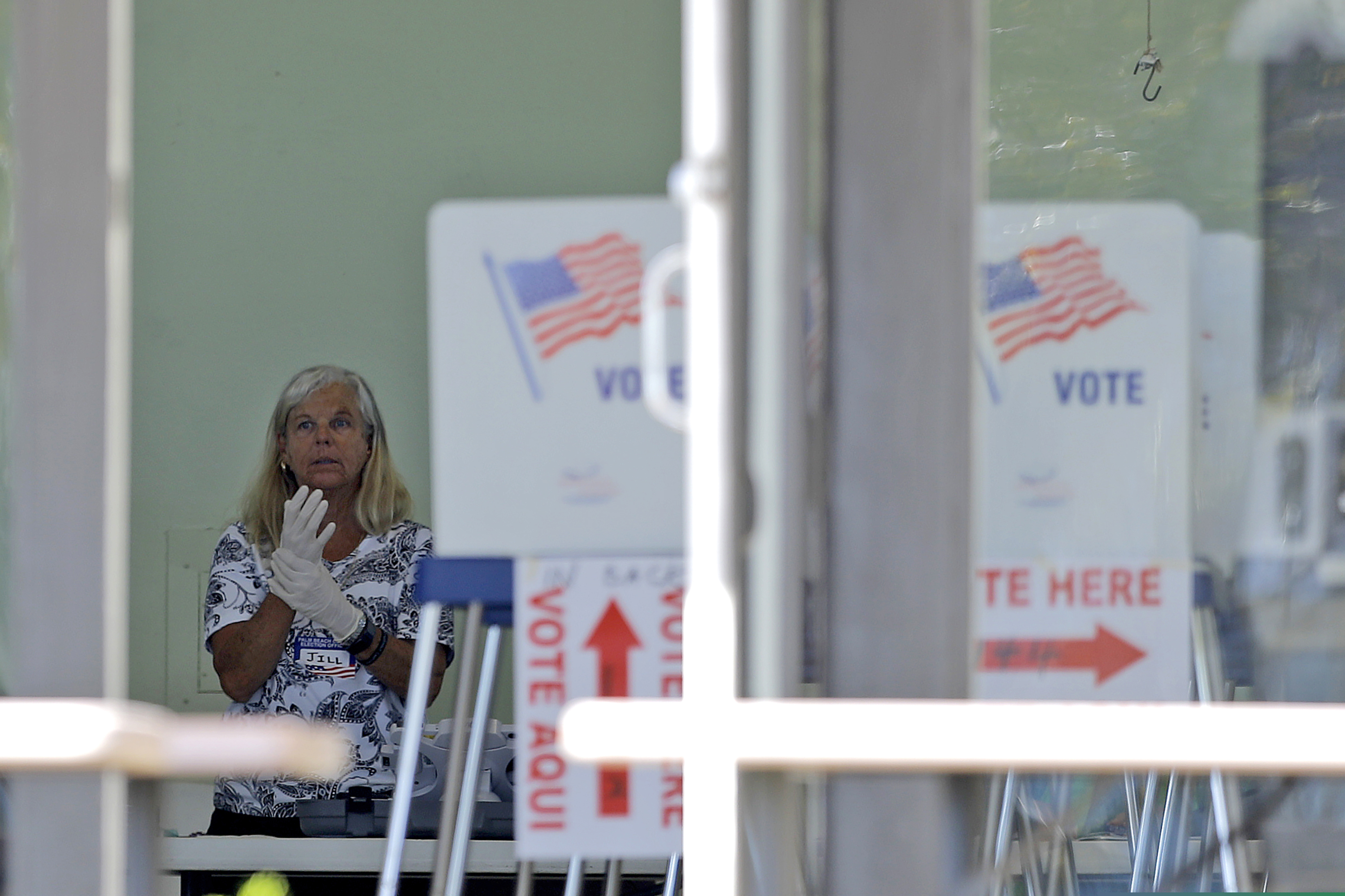 A polling place worker adjusts gloves as she tends to a reception table during the Florida primary election at the First United Methodist Church, Tuesday, March 17, 2020, in Jupiter, Fla. As Florida officials try to contain the spread of the novel coronavirus, the state's voters headed to the polls to cast ballots in the Democratic presidential primary. (AP Photo/Julio Cortez)