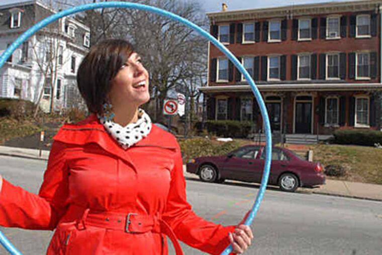 Ashley Ambirge, seen here in downtown West Chester, promotes public hula-hooping on her blog, "The Middle Finger Project," and is into shaking things up. (Bob Williams / For the Inquirer)