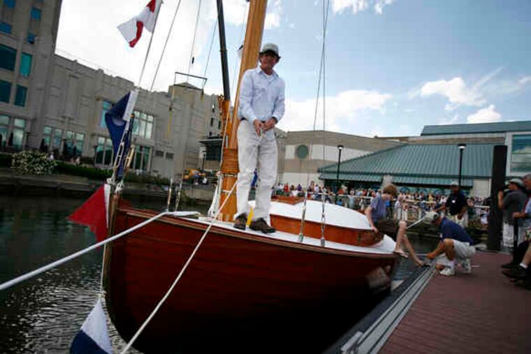 John Brady, who oversaw the new Silent Maid's construction, helps guide it to a dock. The catboat was lowered into the water after being christened at Independence Seaport Museum.