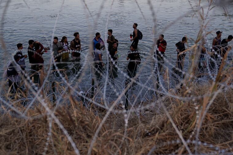 Migrants wait to climb over concertina wire after they crossed the Rio Grande and entered the U.S. from Mexico earlier this year.