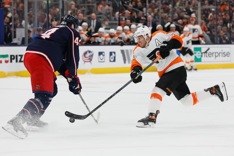 The Flyers' Cam Atkinson shoots the puck as Columbus' Vladislav Gavrikov defends during the first period.