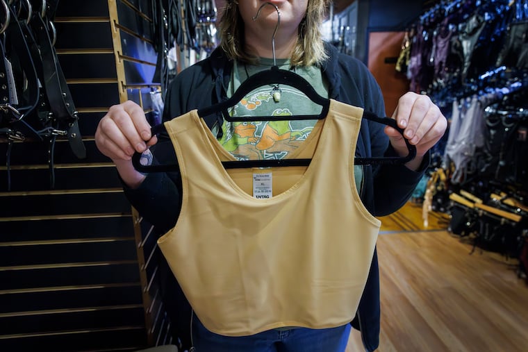 An employee at Passional Boutique & Sexploratorium displays a breast binder for sale at the South Street store. Breast binders are garments that compress chest tissue.