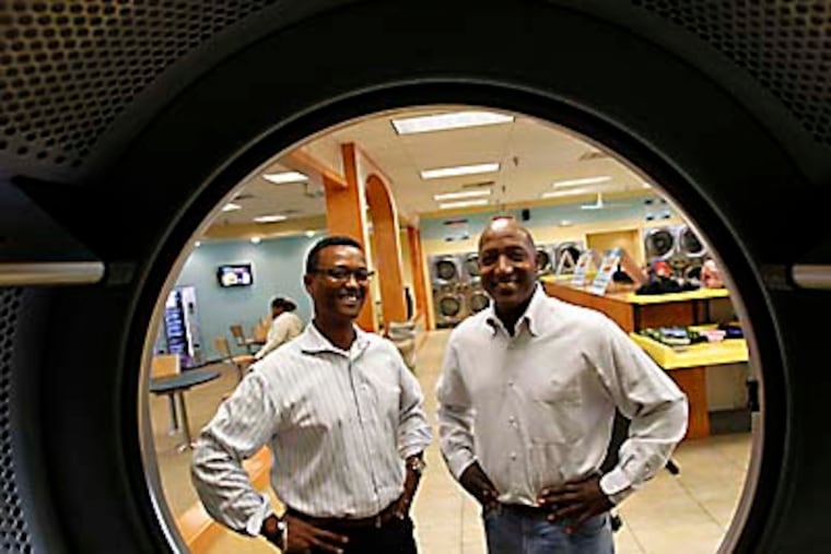 Brian Holland, left, and Tyrone Atkins, right, pose inside their Laundry Cafe laundromat in the Olney Plaza shopping center on October 17, 2012. ( DAVID MAIALETTI / Staff Photographer )