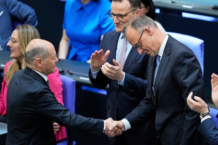 Conservative leader Friedrich Merz is congratulated by outgoing Chancellor Olaf Scholz after being elected new chancellor at the German federal parliament on Tuesday, May 6, 2025.