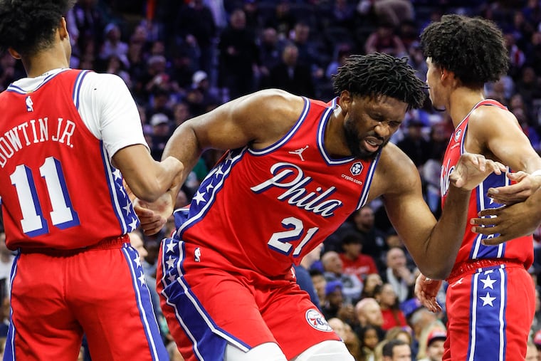 Sixers star Joel Embiid (center) scored 13 points in his season debut on Tuesday.