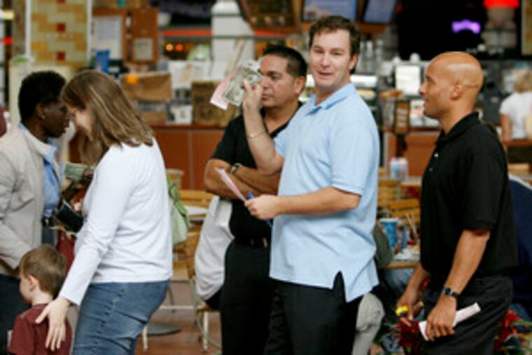 Lines began building earlier this week on both sides of the Delaware River. Fred D'Alfonso waves his money and lottery forms as he waits to buy his tickets Thursday at the Corner News in the Cherry Hill Mall.