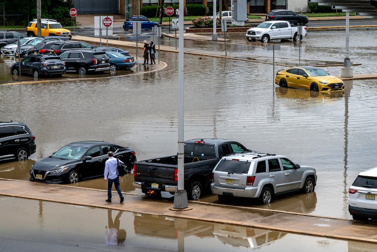Oscar Parra makes his way to his car in the flooded parking lot at the Ferry Avenue PATCO station in Camden on Monday amid a flash-flood threat for the region. His car started, but he planned to wait for the water lever to go down before he tried to drive it away.