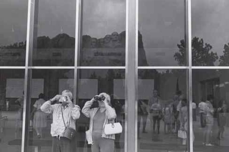 Lee Friedlander's 1969 photograph, "Mt. Rushmore, South Dakota," which is part of the "Spectacle" show, focuses on the viewers, not on the monumental attraction.