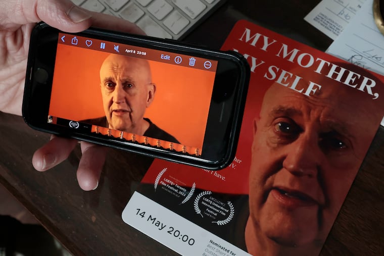 Filmmaker Lary Campbell plays his short film on his phone. The movie card is in the background. Lary was photographed in his Magnolia, N.J. home on Friday, May 3, 2024. Campbell directed and performed the short film, My Mother, My Self. It is the story of the day he told his mother he had HIV. Now the film is being shown at an international film festival in France.