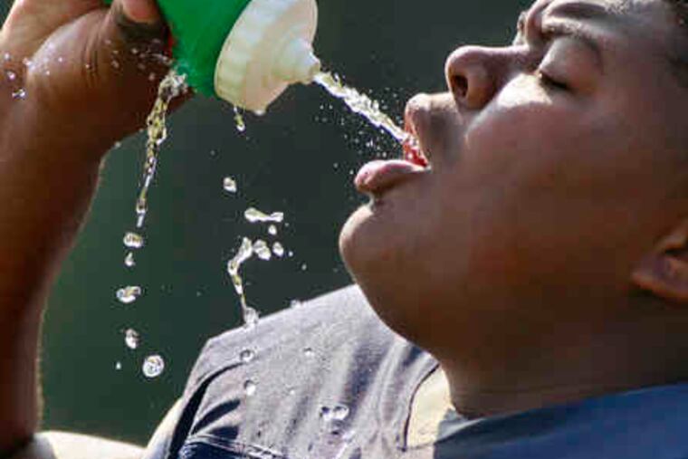 Tuning up in the hot sun is thirsty work , as Timber Creek's Wayne Carter takes a water break during drills.