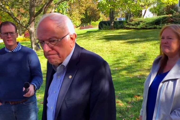 In this image taken from video, Democratic presidential candidate Sen. Bernie Sanders, I-Vt., speaks we reporters outside his home, Tuesday, Oct. 8, 2019, in Burlington, Vt. His wife, Jane O'Meara Sanders listens at right. Sanders says he was "dumb" not to have listened to the symptoms he was experiencing before he was stricken with a heart attack last week.