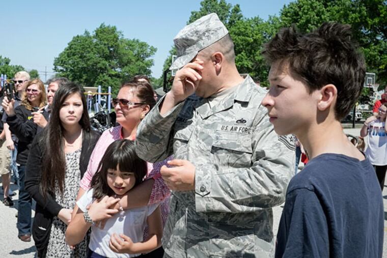 Air Force Sgt. Rafael Encinas, with his wife and children, gets emotional outside Evans Elementary School. Encinas was honored at the school's Memorial Day celebration Friday. (ED HILLE / Staff Photographer)