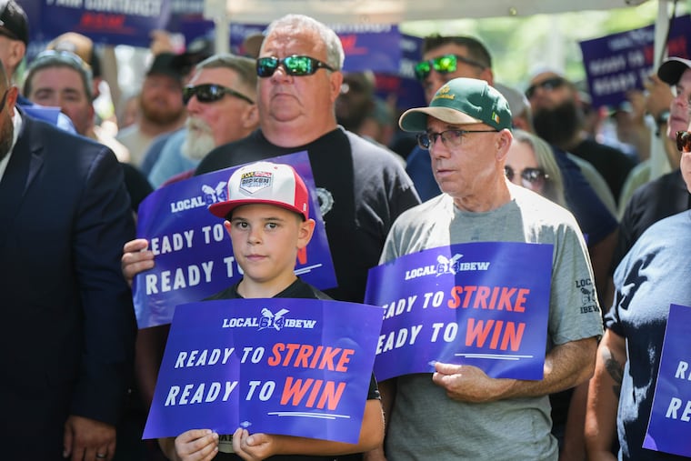 (Back left to right) Bob McGourn, and Tim Hannan, both facilities mechanics, gather with workers and union representatives in Washington Square Park as IBEW Local 614 announce plans for a strike.