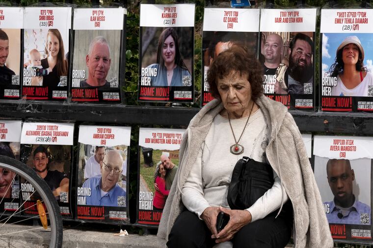 A woman in Tel Aviv pauses Friday near posters of hostages held by Hamas as Israel's cabinet prepared to approve the Gaza ceasefire.