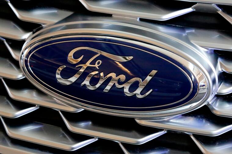 FILE- This Feb. 15, 2018, file photo shows a Ford logo on the grill of a car on display at the Pittsburgh Auto Show. Ford Motor Co. is repackaging a previously announced manufacturing investment in the Detroit area and now says it will spend $900 million and create 900 new jobs over the next four years. Most of the new workers will build a new generation of electric vehicle at Ford’s existing factory in Flat Rock, Michigan, south of Detroit, which will see an $850 million investment.